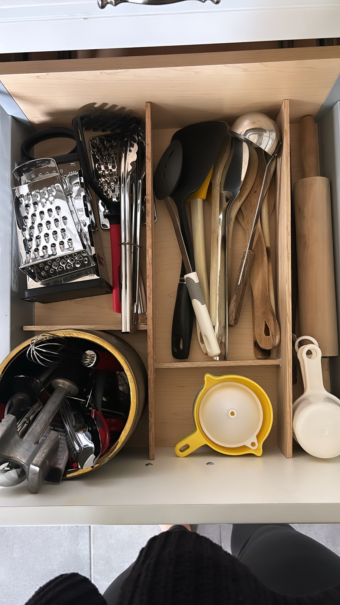 Overhead view of drawer with kitchen utensils organized by wood dividers