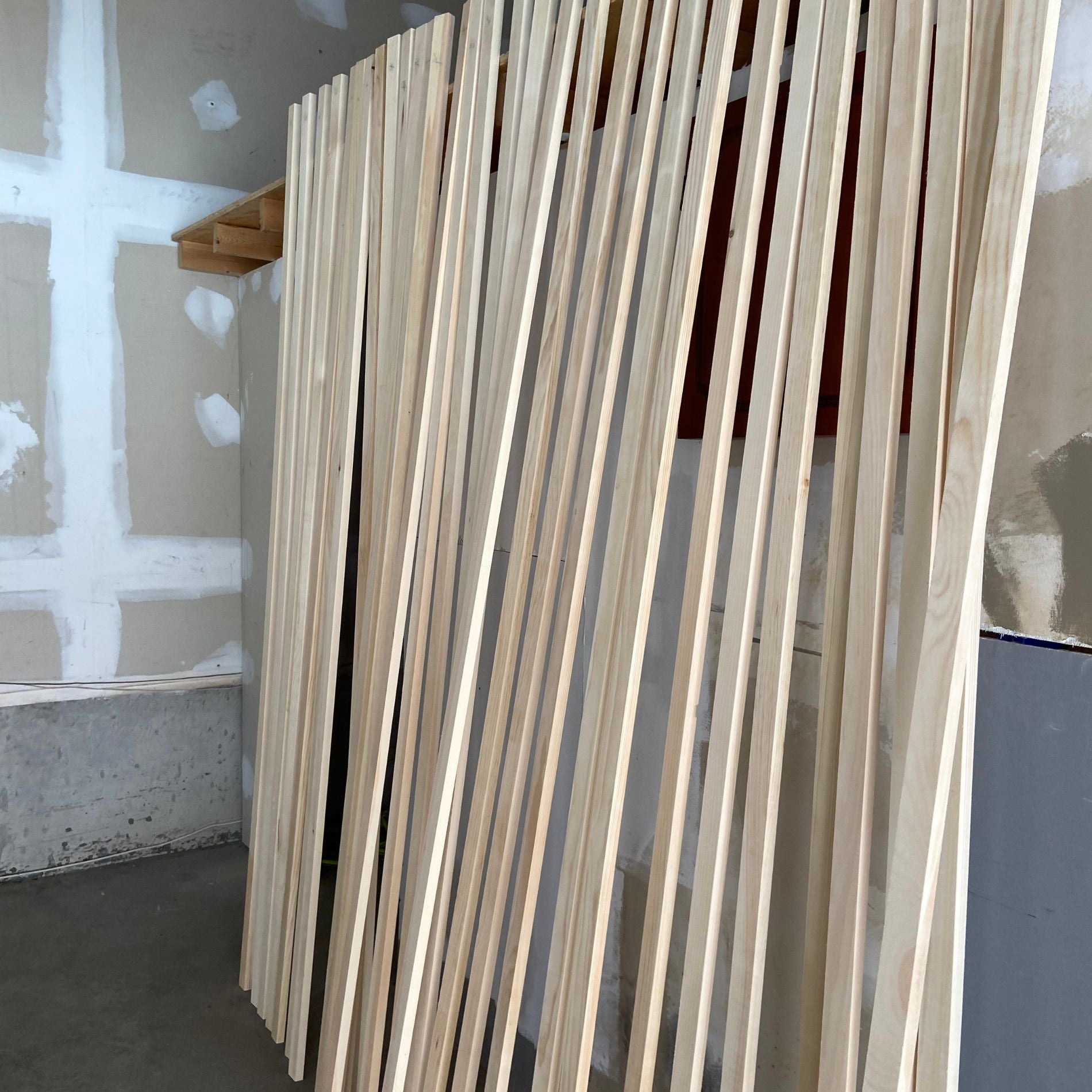 Multiple wood slats standing to dry in garage