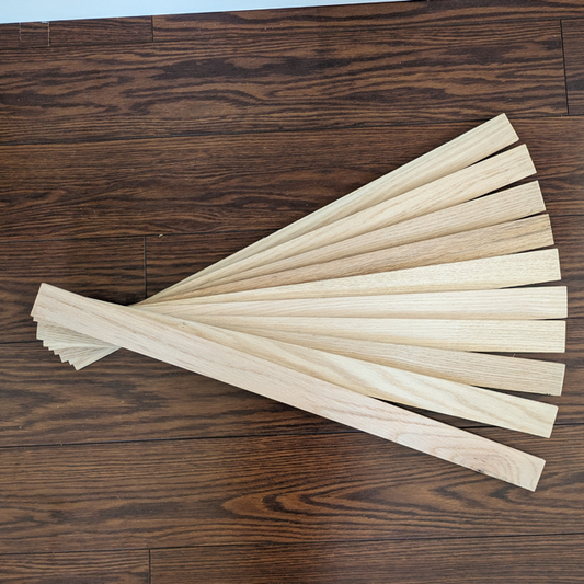 Ten oak wood hobby boards laid on a dark wood floor in the shape of a fan